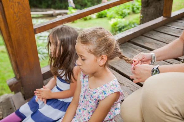 Bambine Sedute Nel Parco Mentre Madre Pettina Intreccia Capelli Della — Foto Stock