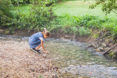 Küçük kız ormandaki akan suyla oynamaya 