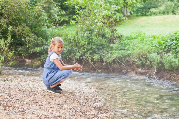 小さな女の子が森に流れる水で遊んで — ストック写真