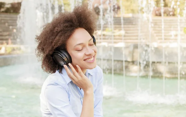 美丽快乐的美国黑人年轻女子的肖像用无线耳机收听音乐 — 图库照片