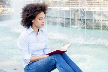 Güzel Afro Amerikalı genç kadın kitap okumak, açık, rahat giyim rahatlatıcı çekici karışık yarış erkek portresi
