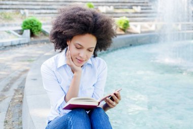 Güzel Afro Amerikalı genç kadın kitap okumak, açık, rahat giyim rahatlatıcı çekici karışık yarış erkek portresi