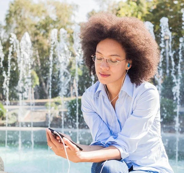 Atractiva Joven Afroamericana Feliz Desgaste Casual Sentada Cerca Fuente Escuchando —  Fotos de Stock