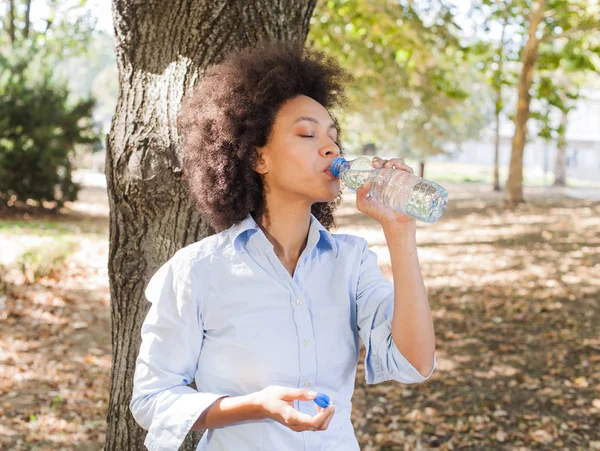 Όμορφη Νεαρή Γυναίκα Αφρικανική Πόσιμο Νερό Από Μπουκάλι Και Χαλάρωση — Φωτογραφία Αρχείου