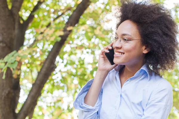 陽気な若い黒の自然で電話で話す女性 屋外のポートレート 見ている側には バック グラウンドで太陽フレア — ストック写真