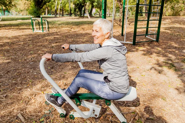 健康成熟的妇女在户外健身房练习 运动衣 运动型老年女性短发 锻炼训练 — 图库照片
