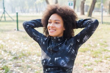 Güzel gülümseyen karışık yarış genç kadın egzersiz spor Afro saç modeli ile açık Fitness Park'ta portresi 