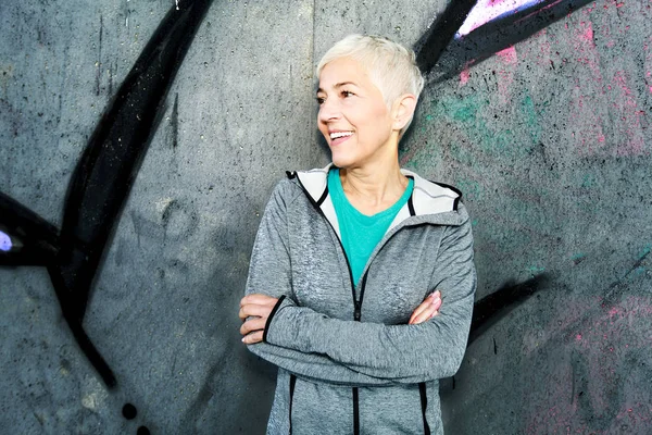 Senior Woman Relax After Running, Leaning On Wall. Short-Gray Hair, Sports Clothes , Looking At The Side