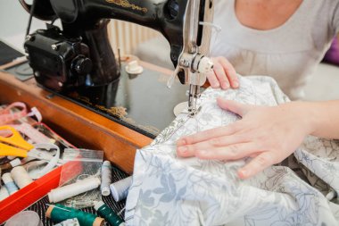 Evde retro dikiş makinesi kullanarak eller closeup.