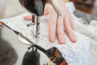 Evde retro dikiş makinesi kullanarak eller closeup.