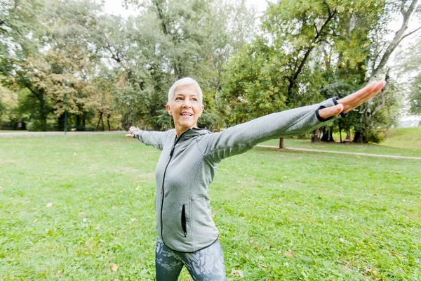 健康中年妇女在运动服做伸展运动在公园 — 图库照片