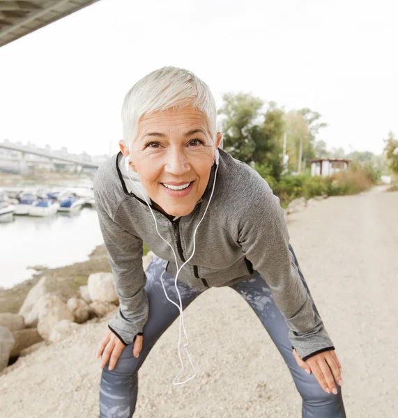 Senior Woman Relax Listening Music With Earphones After Running, Gray-Short Hair, Wear Sports clothes ,Workout Outdoor.