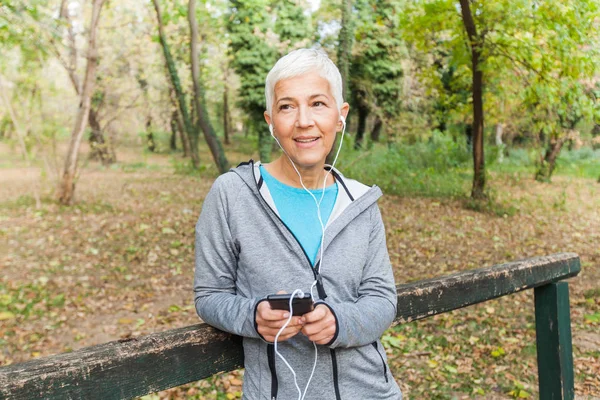 Mujer Mayor Relajarse Escuchando Música Con Teléfono Después Correr Bosque —  Fotos de Stock