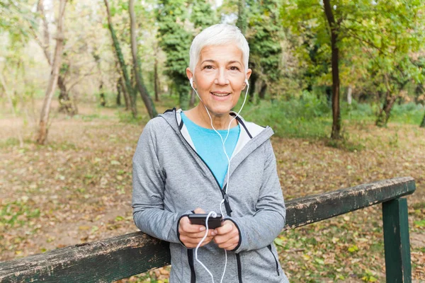 Senior Kvinna Koppla Musik Med Telefonen Efter Jogga Skogen Hälsosam — Stockfoto