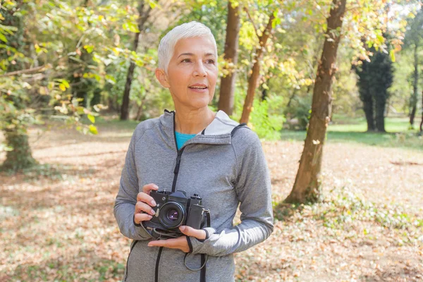 レトロなカメラの森で撮影の準備ができていると中年の女性 — ストック写真