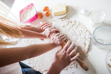 Anne ve kızı pizza hamuru oklava ile birlikte mutfak masasında çalışırken elleri. Üstten görünüm.