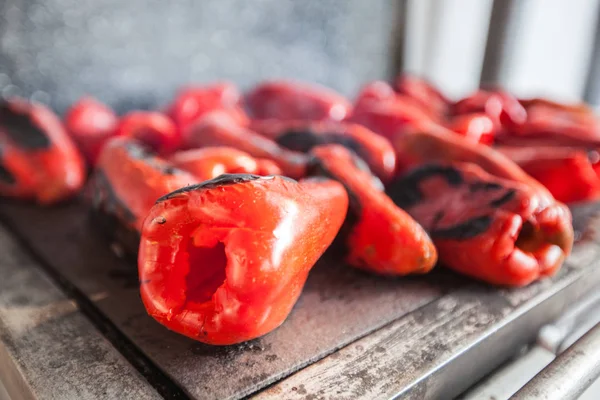 Grilling red peppers on metal plate on wood burning stove - Traditional preparing delicious food in Serbia.