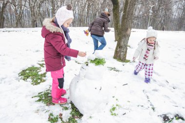 Çocuklar parkta kış gününde bir kardan adam yapmak.