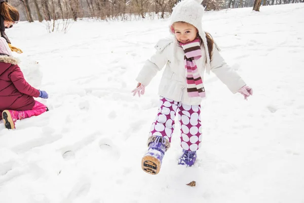 Happy child playing on snow in the park at winter day.