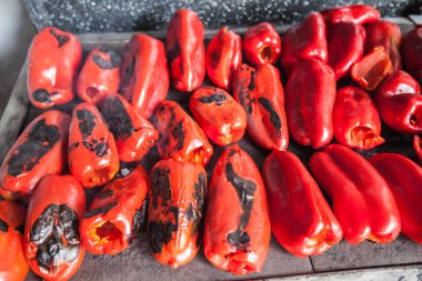 Grilling red peppers on metal plate on wood burning stove - Traditional preparing delicious food in Serbia. clipart