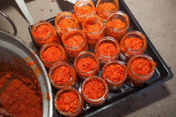 Homemade winter food called ajvar made from roasted red peppers and conserved in glass jars .