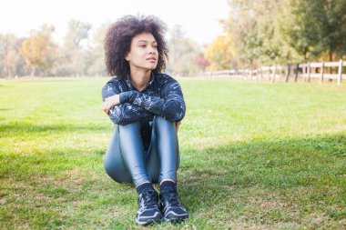 Mutlu sportif Afro Amerikalı genç kadın sakin Park yeşil çimenlerin üzerinde açık egzersiz yaptıktan sonra.