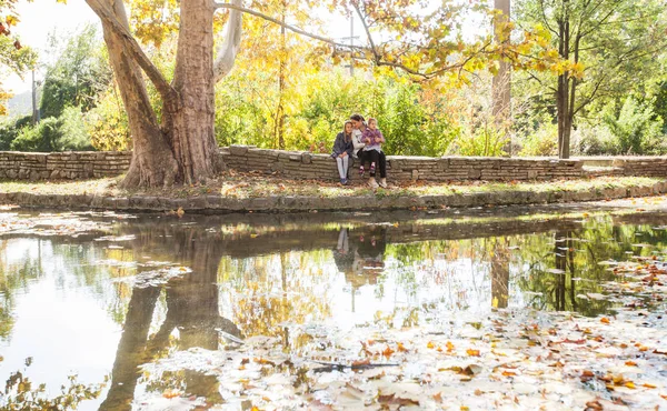 Mutlu aile rahatlatıcı güzel sonbahar günü gölde Park yakınındaki. Su yansıma.