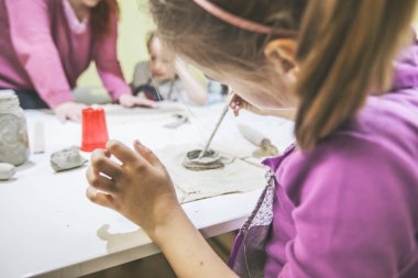 Çömlek atölyesinde kille çalışan yaratıcı çocuklar..