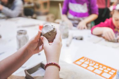 Çömlek atölyesinde kille çalışan yaratıcı çocuklar..