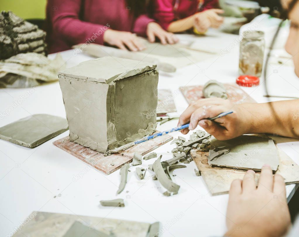 Little artist hands working with clay at pottery workshop