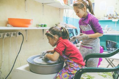Sanat atölyesindeki çömlekçi atölyesinde iki küçük kız yaratıcı bir şeyler öğreniyor. 