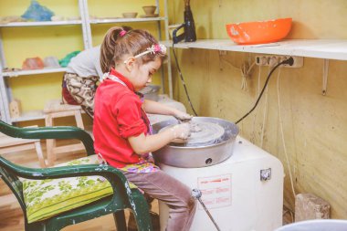 Küçük kız atölyesinde seramik direksiyona kil yapmak yan görünüm.