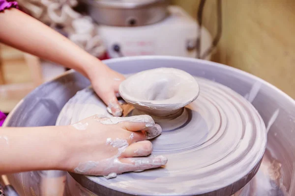 Mãos jovens oleiro trabalhando com argila na roda de cerâmica — Fotografia de Stock
