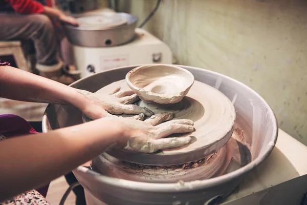 Молодые руки гончара, работающие с глиной на гончарном круге — стоковое фото