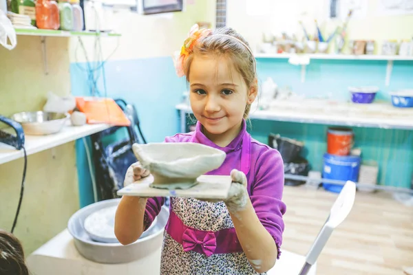 Menina na oficina de cerâmica mostrando vaso de barro — Fotografia de Stock