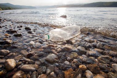Nehir kıyısında plastik şişe atıkları , su kirliliği kavramı 