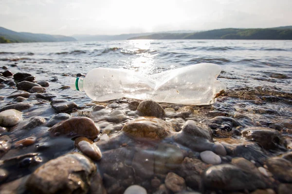 Plastic flessen afval op rivieroever, watervervuiling concept — Stockfoto