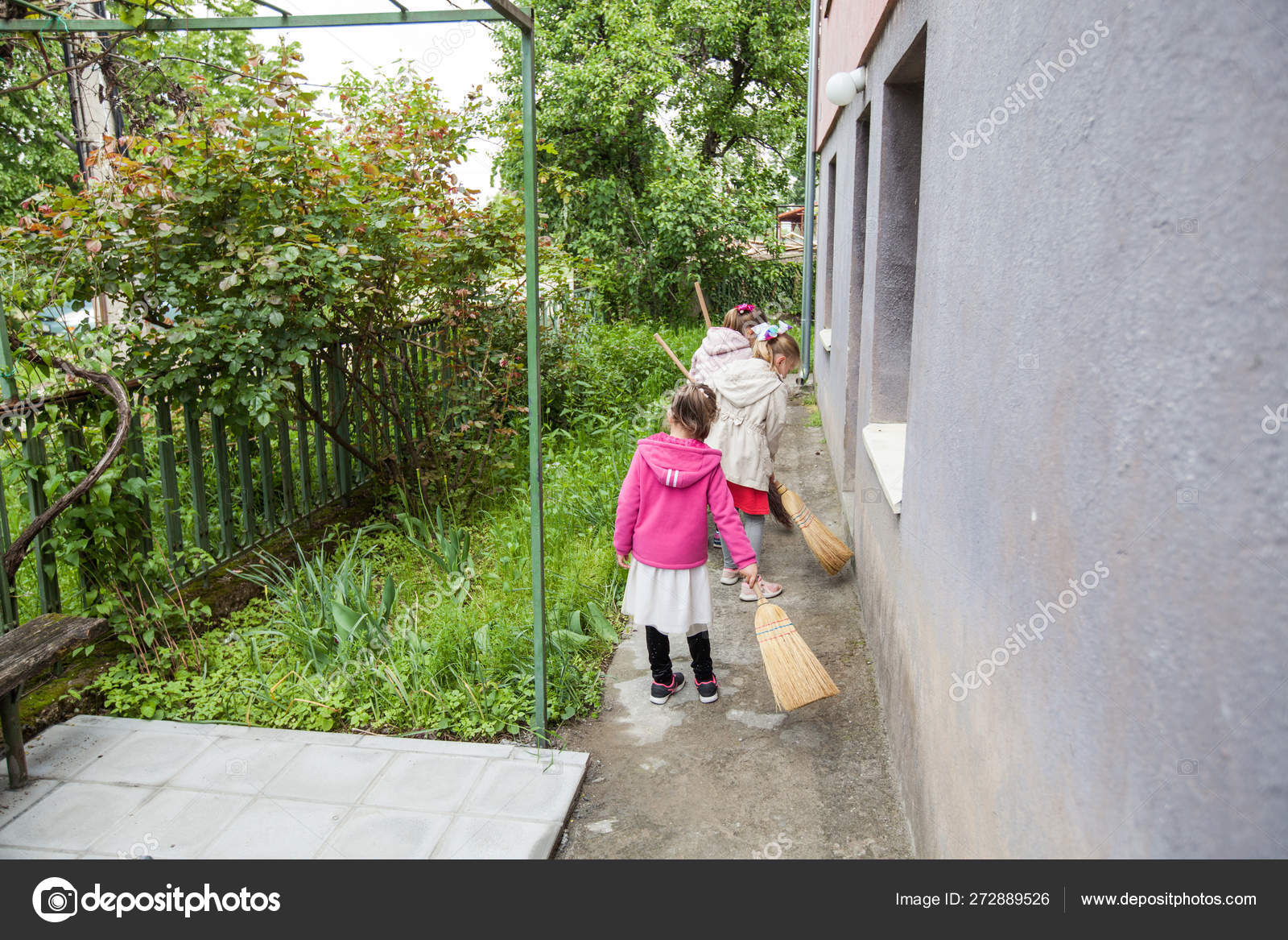 三个小女孩用扫把打扫后院 图库照片 C Mitastockimages