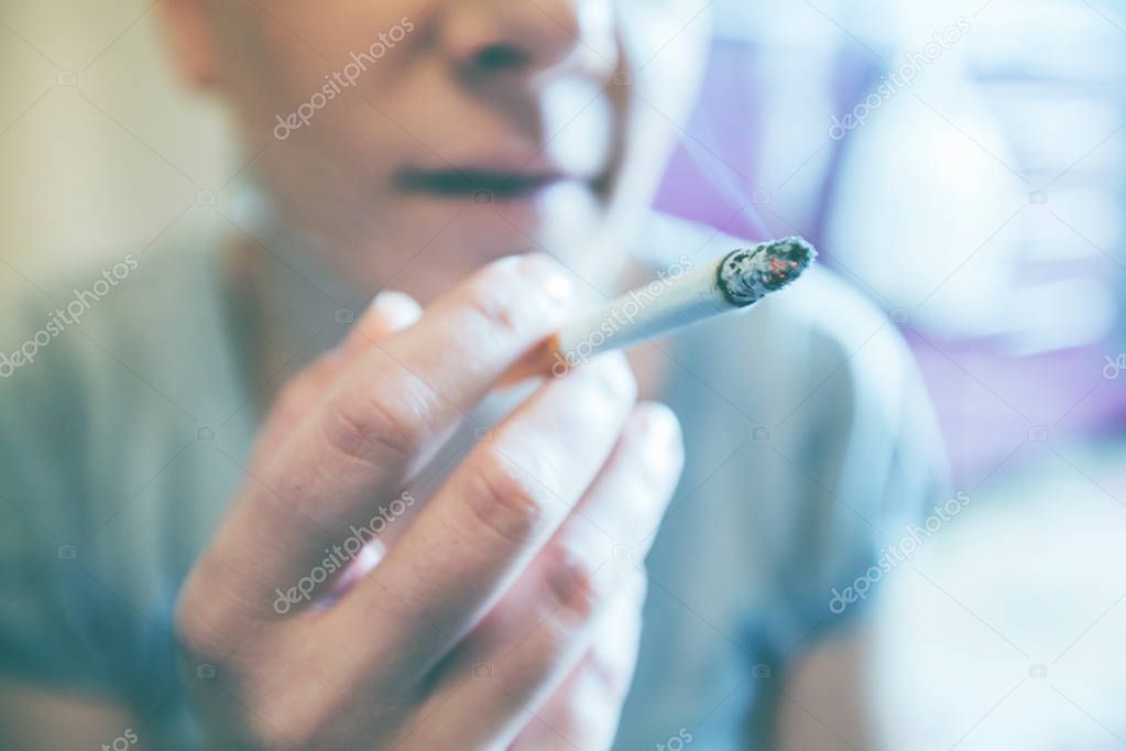 Closeup of depressed woman smoking cigarette 