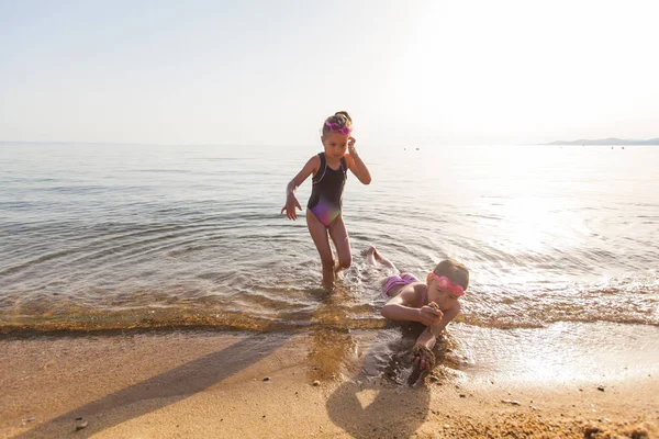 Joyeuses petites filles jouant sur la plage de sable pendant les vacances d'été — Photo