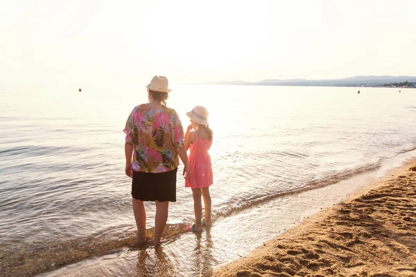 Mutter mit Tochter genießt Sonnenuntergang am Sandstrand im Sommerurlaub — Stockfoto