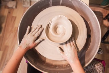 Genç potter eller ile kil çömlek tekerlek üzerinde çalışma