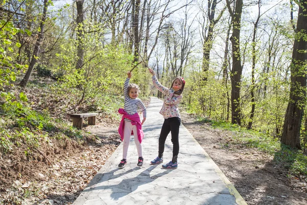 Портрет счастливых двух маленьких девочек, веселящихся в лесу весной — стоковое фото