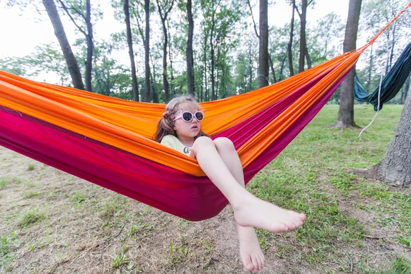 Gelukkig portret van klein meisje ontspannen op hangmat in bos — Stockfoto