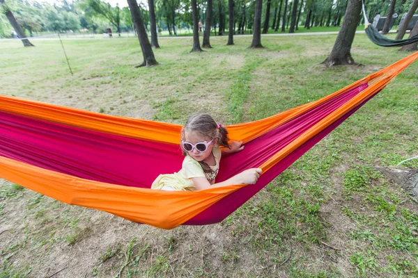 Glückliches Porträt eines kleinen Mädchens entspannen auf der Hängematte im Wald — Stockfoto