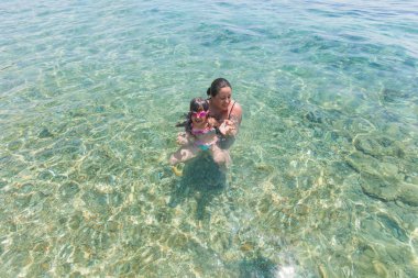 Tatil de denizde birlikte eğlenen anne ve kızı 