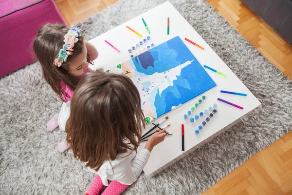 Две маленькие девочки рисуют на холсте — стоковое фото