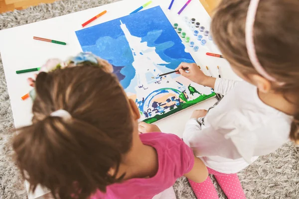 Две маленькие девочки рисуют на холсте — стоковое фото