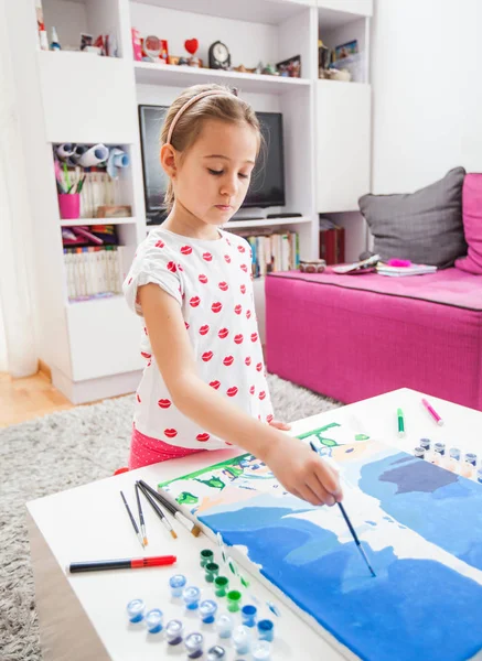 Fokuserad liten konstnär med målarpensel målning på duk — Stockfoto