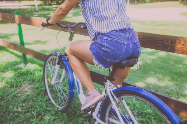 Όμορφη νεαρή γυναίκα καβάλημα ποδήλατο στο πάρκο πίσω όψη — Φωτογραφία Αρχείου